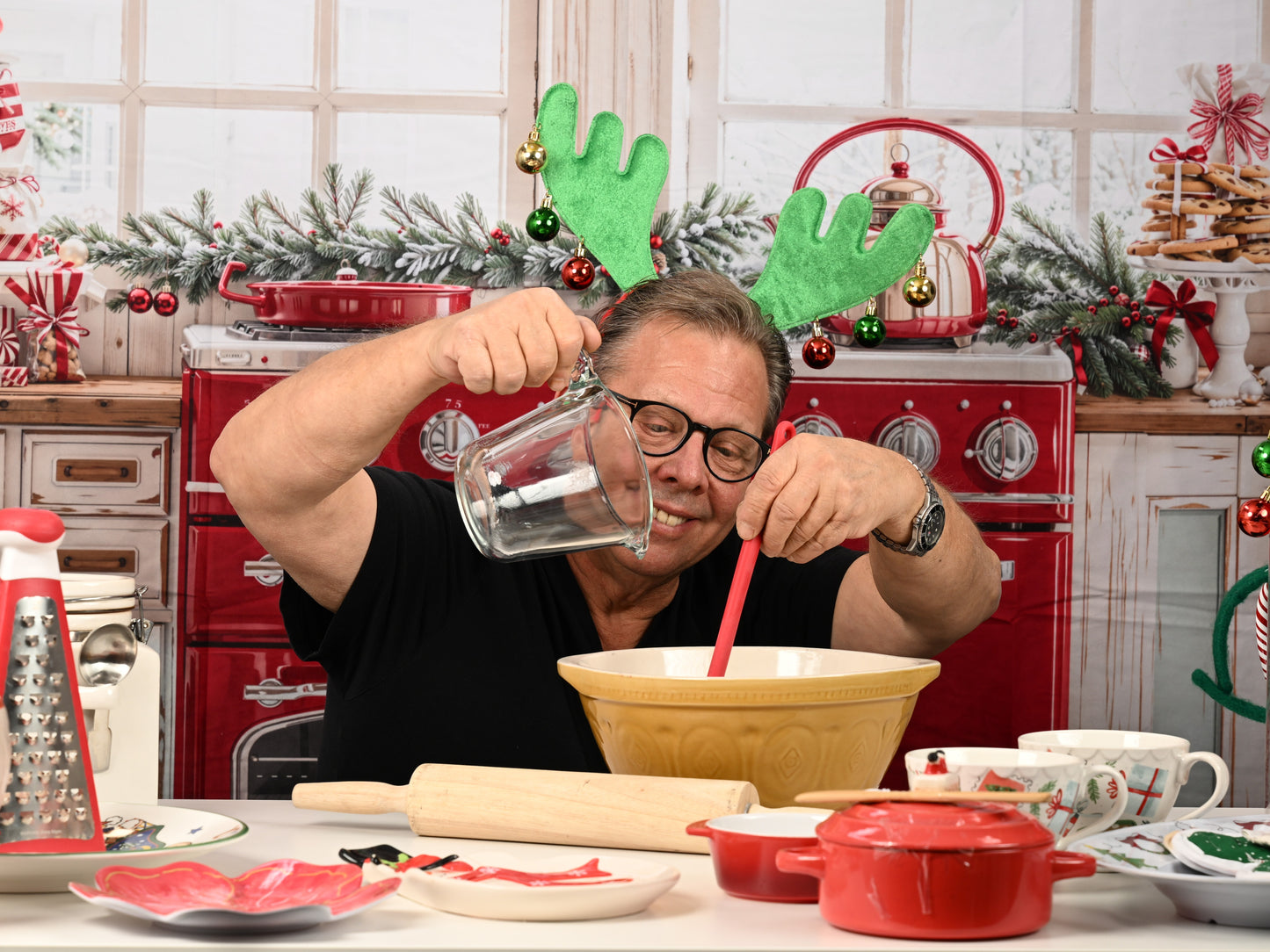 Person in a kitchen with Christmas decorations, pouring liquid into a bowl.